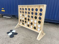 a giant four in a row board game set up on the ground next to two black and white circles