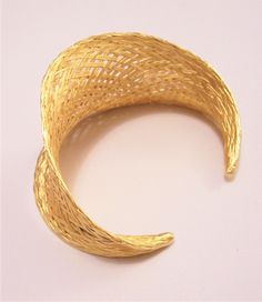 Basket weaved high end luxury strand bracelet bangle cuff vintage gilded gold tone satin smooth bright metal finish open end graduated band golden braided rimmed edge. In excellent never worn vintage condition. Fits most average wrist has a small amount of stretch to the band. Measures 6 inches from end to end, 1 1/2 inches at the widest area of the band and 2 1/2 inches inside. Elegant Adjustable Woven Bracelets, Elegant Woven Adjustable Bracelets, Elegant Gold Cuff Bangle, Adjustable Gold Woven Bracelet, Adjustable Woven Gold Bracelets, Adjustable Gold-tone Elegant Cuff Bracelet, Adjustable Woven Gold Jewelry, Gold Woven Jewelry As A Gift, Gold Woven Jewelry Gift