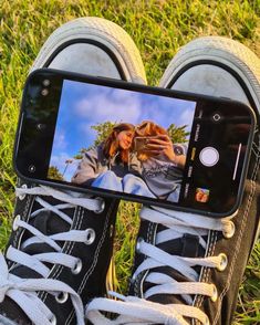 a person's feet are shown with their cell phone in front of them on the grass