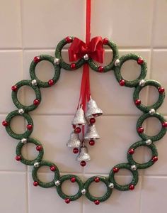 a christmas wreath hanging on the wall with bells and ornaments attached to it's sides