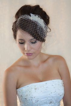 a woman in a wedding dress with a veil on her head, looking down at the camera