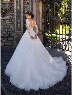 a woman in a wedding dress is standing near an iron gate with flowers on it