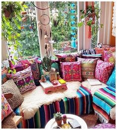 a living room filled with lots of colorful pillows and furniture next to a large window