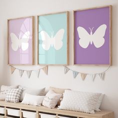 three butterfly paintings hang on the wall above a wooden bench with pillows and throw pillows