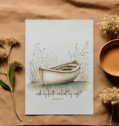 there is a card with a boat on it next to some flowers and a cup