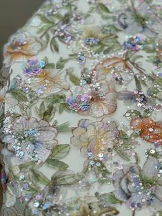 an embroidered fabric with flowers and sequins on the bottom is seen in this close up photo