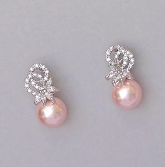 "These elegant bridal earrings have been created using a Swarovski round pearl, crowned in a crystal studded fancy post. These super pretty earrings are perfect if you're a bride who likes a smaller earring that you can forget you're wearing on the day. Lucia is ideal for the bridal party also. We used peach blush in these photos, but ivory white and other shades are available. Measurements: L= .75\" (2 cm) approx Nickel free & allergy free posts. Cz crystals set in rhodium. 💝 All our jewel Crystal Wedding Earrings, Crystal Earrings Wedding, Bridal Earrings Pearl, Earrings Crystal, Bow Earrings, Crystal Wedding, Crystal Drop Earrings, Pretty Earrings, Small Earrings