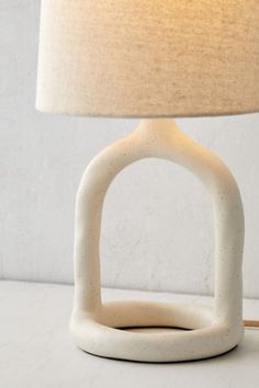 a white table lamp sitting on top of a counter next to a light fixture with a beige shade