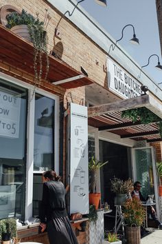 the outside of a restaurant with people sitting at tables and standing in front of it