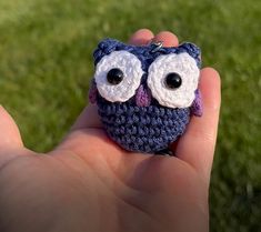 a small crocheted owl with big eyes in someone's hand