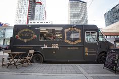 the food truck is parked on the side of the road in front of tall buildings