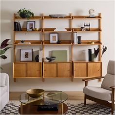 a living room filled with furniture next to a wall mounted bookshelf and a glass top coffee table