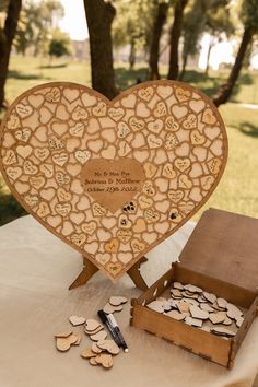 a heart shaped wooden box sitting on top of a table next to a cardboard box filled with hearts