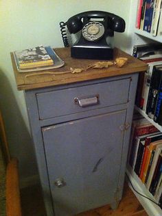 an old fashioned telephone sits on top of a cabinet in front of a bookshelf