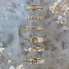 five different types of wedding rings sitting next to each other on a marble surface with flowers in the background