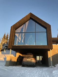 a car is parked in front of a large windowed building with snow on the ground