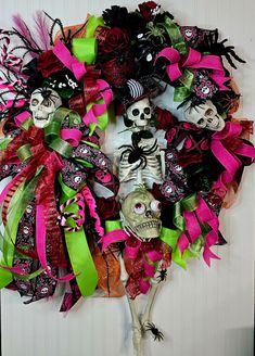 a wreath decorated with skulls, roses and green ribbons is hanging on the wall in front of a door