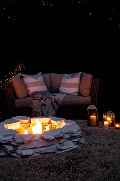 a fire pit surrounded by candles and pillows