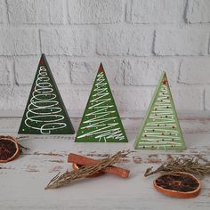 three wooden christmas trees sitting on top of a table next to an orange and cinnamon peel