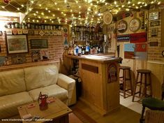 a bar with lots of bottles on the wall and lights hanging from it's ceiling