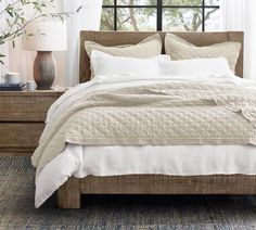 a bed with white linens and pillows in front of a window, next to a dresser