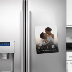 a couple kissing in front of a refrigerator with magnets on the door and an ad for save the date