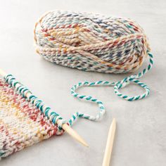 two skeins of yarn next to a knitting needle