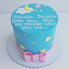 a blue cake decorated with stars and a pink bow on a white platter that says twinkle little star how we wonder what you are