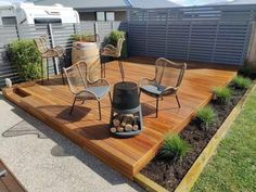 an outdoor deck with chairs, fire pit and potted plants on the side walk