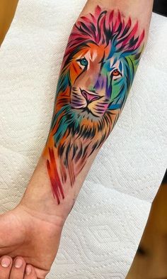 a colorful lion tattoo on the left arm and wrist is shown in this photo, it appears to be painted with watercolors