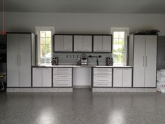 a kitchen with white cabinets and gray counter tops in the middle of an empty room