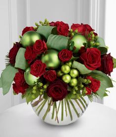 a vase filled with red roses and green ornaments