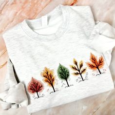 This sweatshirt is perfect for autumn lovers! The colourful embroidered leaves make this crewneck ideal for this autumn, looks great with jeans or leggings. Unisex relaxed fit sweatshirt 80% Cotton and 20% Polyester  Processing time varies depending on the sweatshirt colour and size. If you have a certain date when you need your item, please contact me before ordering to be sure that I can send it to you in time. Colours may vary due to screen resolution, flash and effect used. Machine wash in c Fall Floral Embroidered Crew Neck Sweater, Custom Embroidered Fall Sweatshirt, White Floral Embroidered Sweatshirt For Fall, Multicolor Embroidered Cotton Tops For Fall, Fall Cotton Sweatshirt With Floral Embroidery, Casual Fall Sweatshirt With Floral Embroidery, Crew Neck Top With Custom Embroidery For Fall, Fall Cotton Sweater With Multicolor Embroidery, Fall Crew Neck Sweatshirt With Custom Embroidery