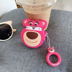 a pink bear keychain sitting on top of a table next to a cup of coffee