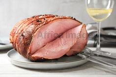 sliced ham sitting on a plate next to a glass of wine