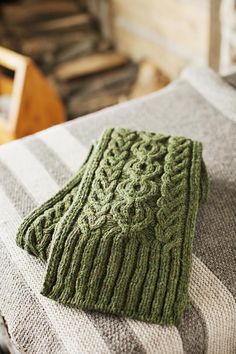 a green knitted mitt sitting on top of a bed next to a wooden chair