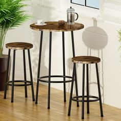 three stools and a table in front of a potted plant on a hard wood floor