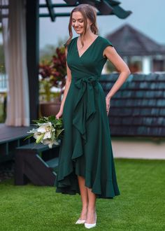 a woman in a green dress is standing on the grass with her hands on her hips