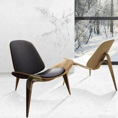 two chairs sitting next to each other in front of snow covered trees and window sill