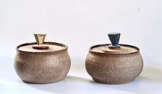 two brown pots with handles are sitting side by side