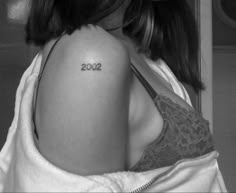 a woman with a small tattoo on her upper arm and the word 2012 written in cursive font