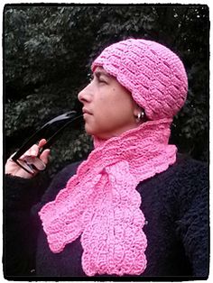 a woman wearing a pink knitted hat and scarf with a pipe in her mouth