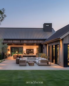 an outdoor living area with couches and tables in front of a barn style house