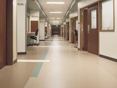 an empty hospital hallway with chairs and desks on either side of the corridor door