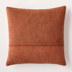 an orange pillow sitting on top of a white wall