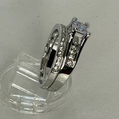 two wedding rings sitting on top of each other in front of a clear display case