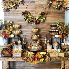 a table topped with lots of food next to a wall covered in fall leaves and wreaths