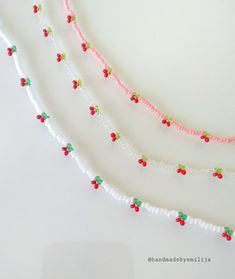 three strands of beaded necklaces with red, green and white beads on them