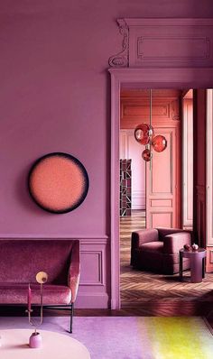 a living room with purple walls and furniture in the center, along with a large mirror on the wall