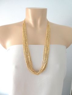 "Long necklaces for women boho layered. Measures 30\". It has 12 strands. ❤ PROCESSING AND SHIPPING Most orders are made and shipped out in one business day. Please check delivery timeframes for your location on the description below. ❤ CUSTOM ORDERS If you like this item in a different color, send me a message indicating: color, size and quantity needed. I will send you a link for a \"custom order\" and you'll be able to place the order there. If you like this item with some variations such as Gold Multi-strand Layered Necklace With Beads, Gold Beaded Multi-strand Layered Necklace, Gold Multi-strand Necklace With Gold Beads, Bohemian Gold Layered Necklace With Round Beads, Gold Beaded Necklaces For Layering, Gold Beaded Multi-strand Necklace, Gold Double Strand Beaded Necklaces With Tiny Beads, Gold Multi-strand Beaded Necklace, Gold Double Strand Beaded Necklace With Tiny Beads